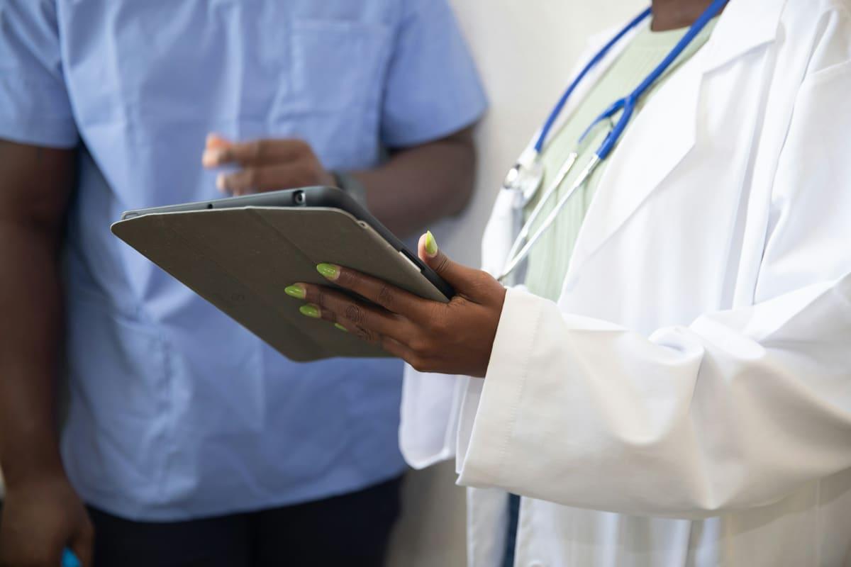 A healthcare professional reviewing records on a tablet with a colleague