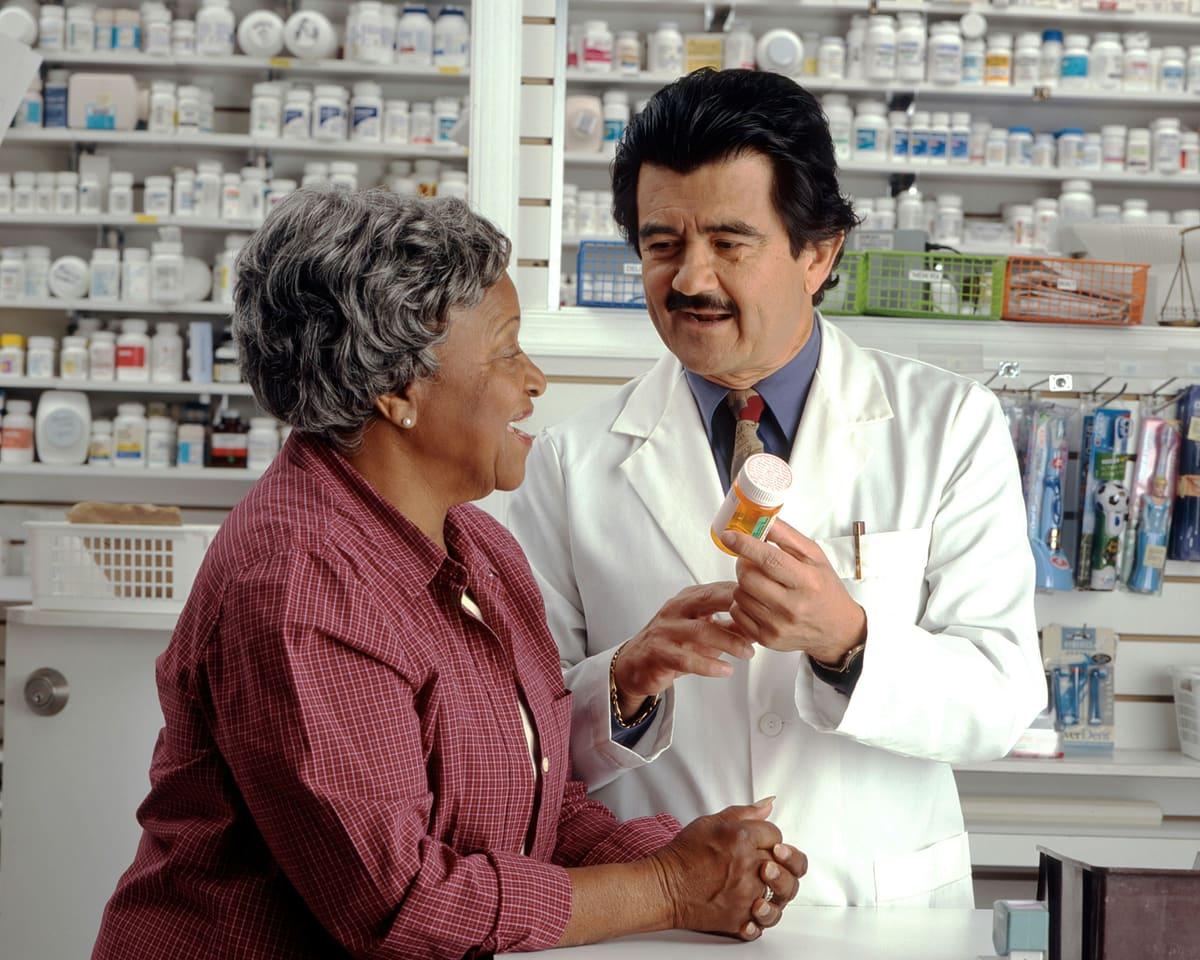 A pharmacist handing medication to a patient across the counter